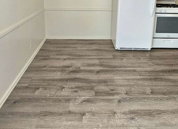 A white fridge in a room with wooden flooring.