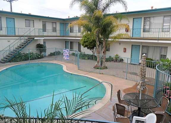 A pool surrounded by chairs and a fence.