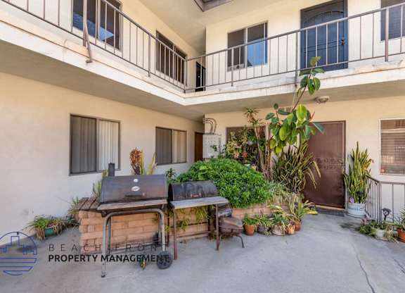 A balcony with a grill and potted plants.