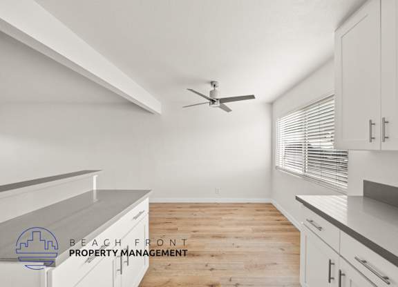 A kitchen with a ceiling fan and wooden flooring.