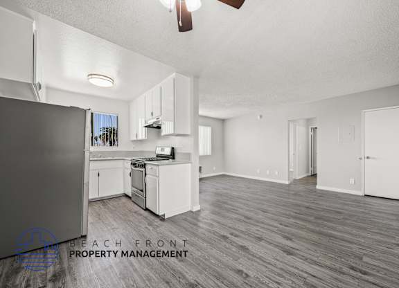 A spacious kitchen with white cabinets and a wooden floor.