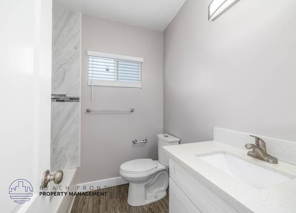 A white bathroom with a toilet, sink, and a window.