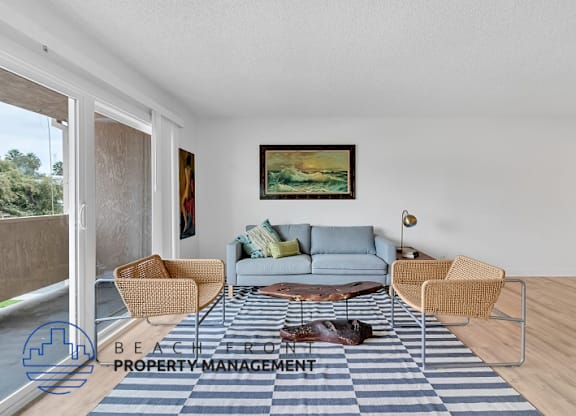 A living room with a blue couch, a painting on the wall, and a dog on the floor.