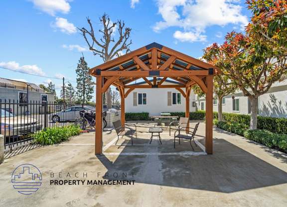 a patio with a picnic table and chairs under a wooden pavilion