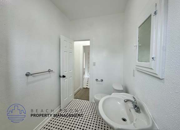 A bathroom with a white sink and a black and white floor.