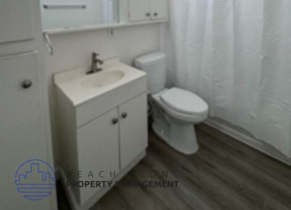 A white bathroom with a toilet, sink, and shower curtain.