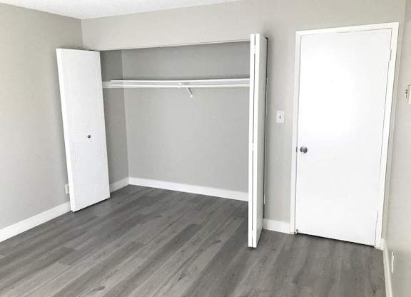 A room with a white door and a white closet with a shelf.