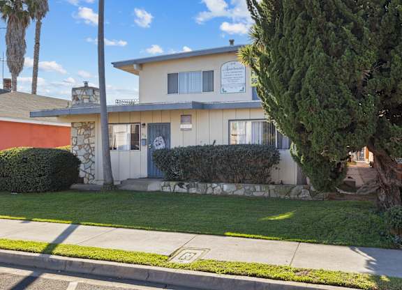 A house with a white fence and a green tree in front.