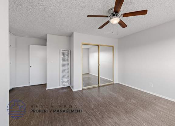 the spacious living room of an apartment with a ceiling fan