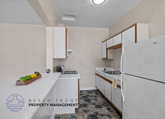 A kitchen with a refrigerator, sink, stove and cabinets.