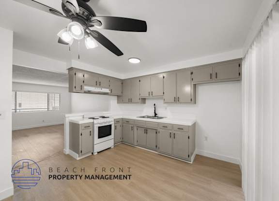 A kitchen with a ceiling fan and a logo for Beach Front Property Management.