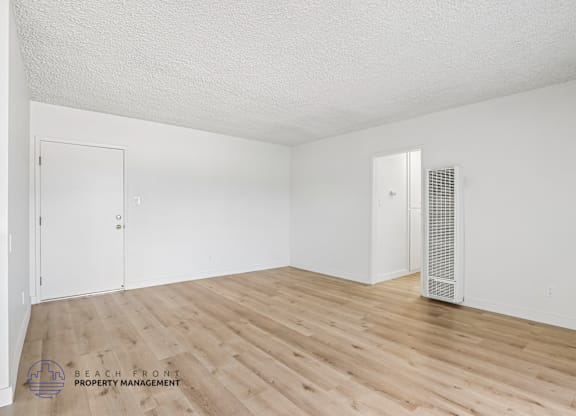 A spacious room with wooden flooring and a white ceiling.
