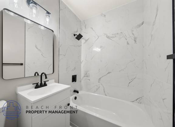 A bathroom with a marble wall and a white sink.