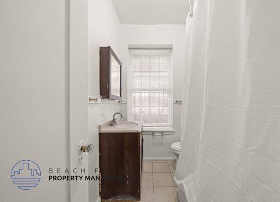 A small bathroom with a toilet, sink, and window.