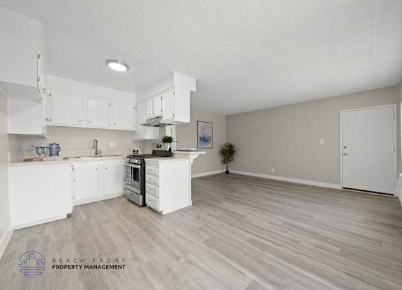A spacious kitchen with white cabinets and a wooden floor.