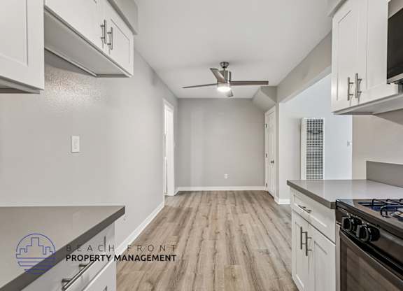 A kitchen with a stove top oven and a fan on the ceiling.