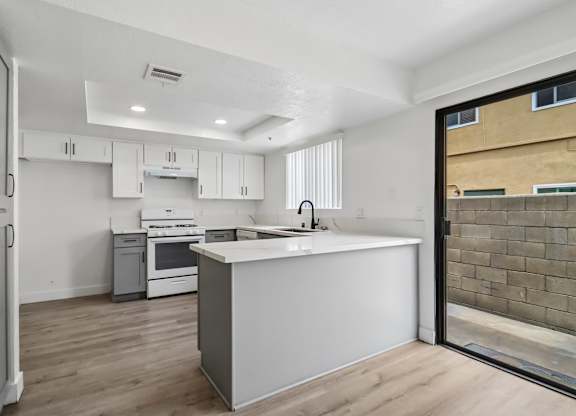 A modern kitchen with white cabinets and a wooden floor.