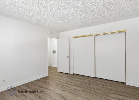 A room with a white door, a white wall, and a white closet.