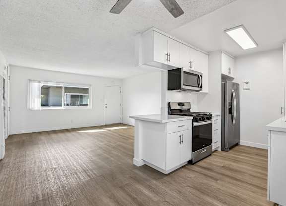 A kitchen with white cabinets and a wooden floor.