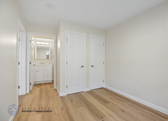A white bedroom with a dresser and a mirror.