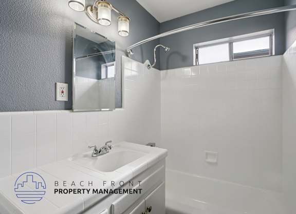 A bathroom with a sink, mirror, and a window.
