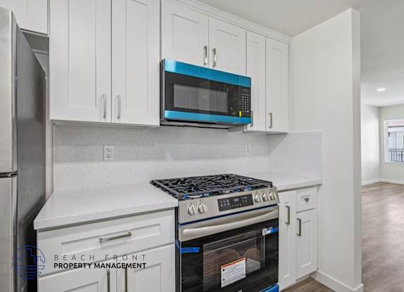 A kitchen with white cabinets and a blue microwave.