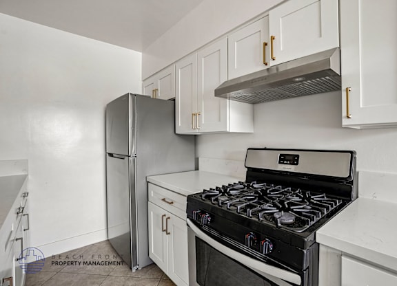 A modern kitchen with a stove, refrigerator, and cabinets.