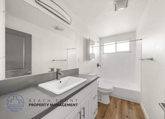 A bathroom with a sink, toilet, and mirror.