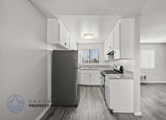 A kitchen with white cabinets and a refrigerator in a property.