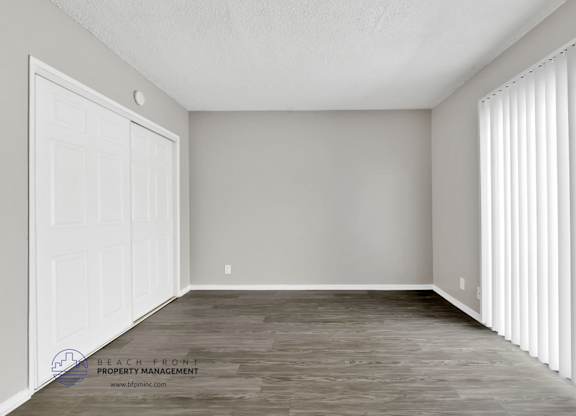 A room with a white door and a window with white blinds.