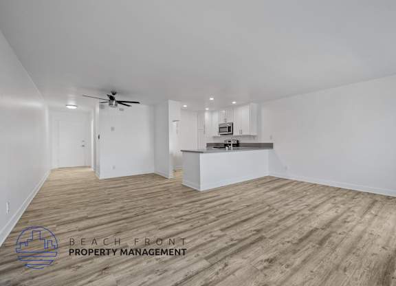 A spacious room with wooden flooring and a ceiling fan.