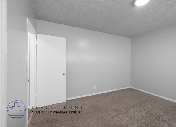 the spacious living room of an apartment with white walls and carpet