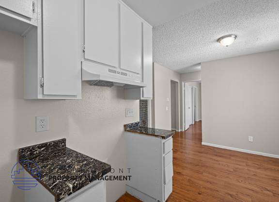 A kitchen with a granite countertop and white cabinets.