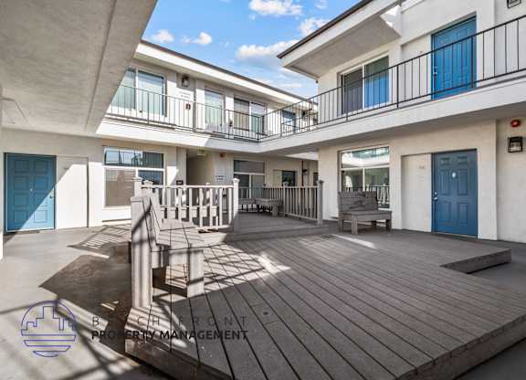 A balcony with a table and chairs is on the second floor of a building.
