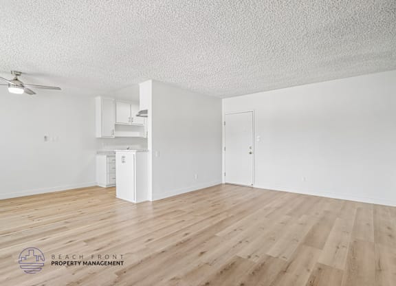 A spacious room with wooden flooring and a ceiling fan.