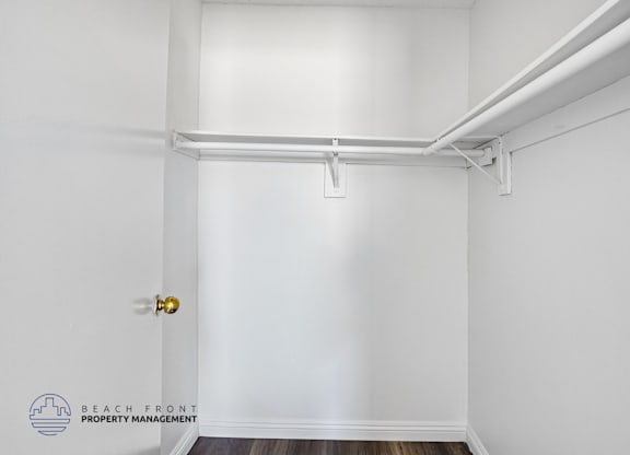 A white door with a gold handle is on the left side of a white wall.