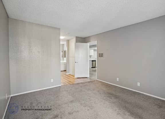 A spacious room with a carpeted floor and a doorway leading to another room.