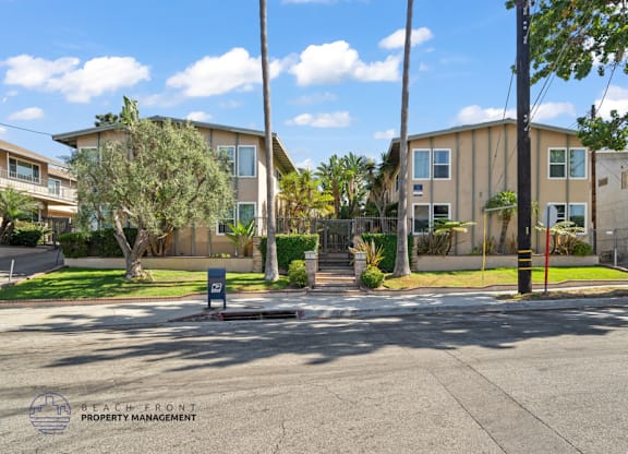 A street view of a residential area with apartment buildings and a sign for Beach Front Property Management.