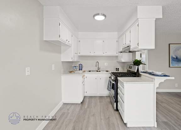 A kitchen with white cabinets and a wooden floor.