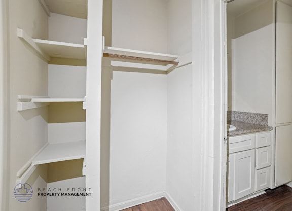 A white kitchen with a refrigerator, sink, and cabinets.