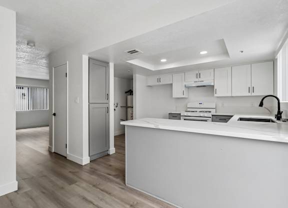 A modern kitchen with white cabinets and a white countertop.