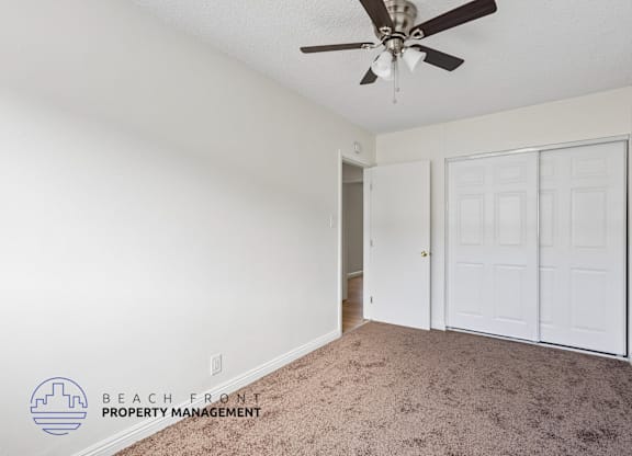 A room with a ceiling fan and carpeted floor.