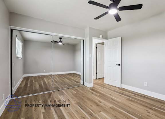 A room with a ceiling fan and a mirror on the wall.