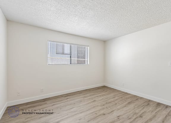 A room with a window and wooden flooring.