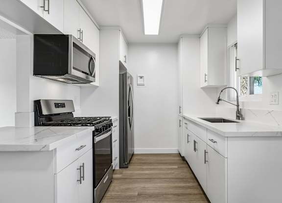A modern kitchen with white cabinets and appliances.
