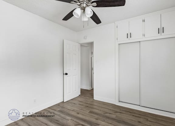 A room with a ceiling fan and wooden flooring.