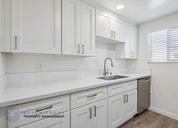 A kitchen with white cabinets and a sink.