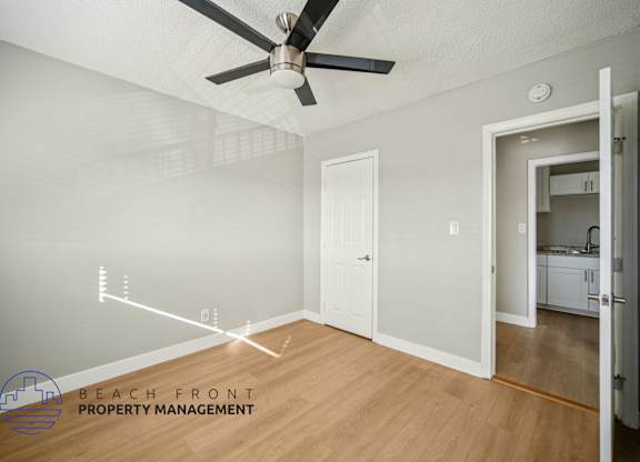 A room with a ceiling fan and a door leading to another room.