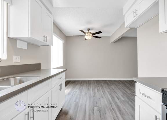 A kitchen with white cabinets and a ceiling fan.