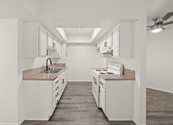 A kitchen with white cabinets and a wooden floor.